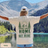 Home Is Out Here Comfort Colors 1717 graphic t-shirt featuring mountain, pine trees, and wilderness artwork with a small left chest logo and large back print.