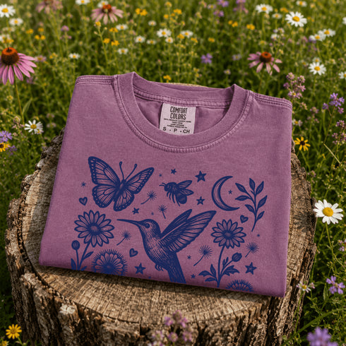 Vintage-inspired hummingbird and butterfly wildflower graphic printed on a Berry colored Comfort Colors t-shirt.