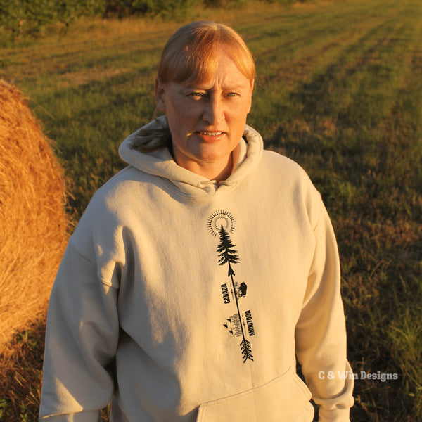 This hoodie features a unique design that showcases the beauty of Manitoba's nature icons, including prairie wheat, geese, bison, a camping scene, trees, and a big sun.