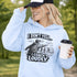 Woman wearing a grey hoodie with “I Don’t Yell I Coach Loudly” soccer coach design featuring coach pointing on sideline with players in background