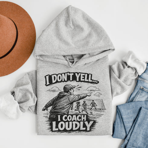 “I Don’t Yell I Coach Loudly” hoodie soccer coach design featuring coach pointing on sideline with players in background