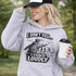 Woman wearing a grey hoodie with “I Don’t Yell I Coach Loudly” soccer coach design featuring coach pointing on sideline with players in background