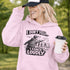 Woman wearing a grey hoodie with “I Don’t Yell I Coach Loudly” soccer coach design featuring coach pointing on sideline with players in background