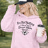 Woman wearing a hoodie that says “I’m Not Yelling This Is My Soccer Mom Voice” with a soccer ball heart design, standing on a soccer field