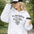 Woman wearing a hoodie that says “I’m Not Yelling This Is My Soccer Mom Voice” with a soccer ball heart design, standing on a soccer field