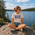 Woman sitting on a rock by a lake wearing a 'It's Lake Time' t-shirt.