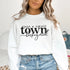 Small Town Hockey Mom sweatshirt with black typography design on a cozy white crewneck, perfect for rink moms and hockey season apparel