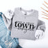 Small Town Hockey Mom sweatshirt with black typography design on a cozy white crewneck, perfect for rink moms and hockey season apparel