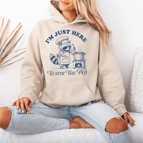 Meet your new favorite hoodie—starring a sarcastic raccoon who’s as skilled at cooking up drama as stirring actual soup.