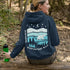 This hoodie features a silhouetted polar bear wandering across layered frozen prairie hills, this design captures the quiet majesty of nature.
