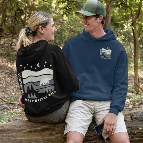 This design features a minimalist polar bear silhouette, gracefully wandering across layered prairie hills, framed by dense pine forests and a serene night sky.