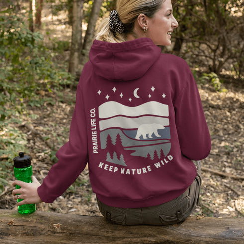 This design features a minimalist polar bear silhouette, gracefully wandering across layered prairie hills, framed by dense pine forests and a serene night sky.