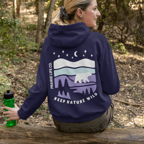 Featuring a sleek polar bear silhouette wandering through layered frozen prairie hills, this hoodie design evokes the serenity of untouched nature.