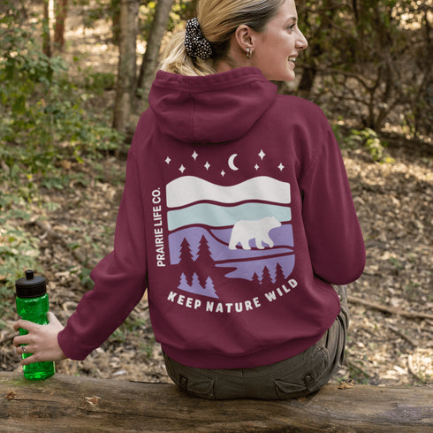 Featuring a sleek polar bear silhouette wandering through layered frozen prairie hills, this hoodie design evokes the serenity of untouched nature.