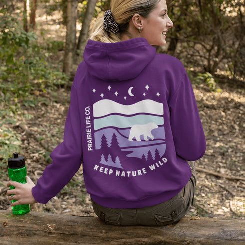 Featuring a sleek polar bear silhouette wandering through layered frozen prairie hills, this hoodie design evokes the serenity of untouched nature.