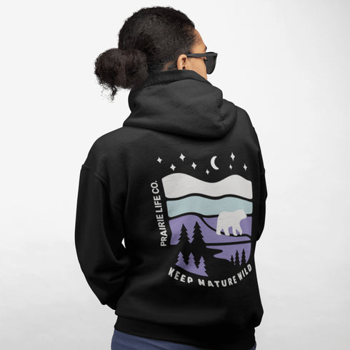 Featuring a sleek polar bear silhouette wandering through layered frozen prairie hills, this hoodie design evokes the serenity of untouched nature.