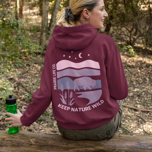 The hoodie showcases a bison standing above wheat with an open prairie sky, blending modern style with the wild spirit of the Canadian countryside.