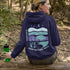 This hoodie features a color-blocked design in pastel blue and purple hues. The graphic showcases a powerful bison standing above wheat with an open prairie sky