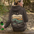 This hoodie features rolling prairie hills, a glowing campfire beside a cozy tent, towering pines, and a star-filled night sky complete with a crescent moon.