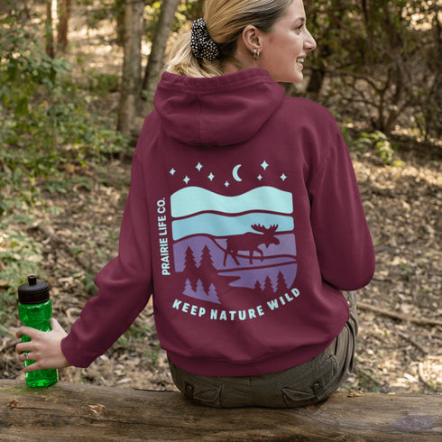 Featuring a bold moose silhouette set against a serene forest landscape, this design celebrates adventure, conservation, and life beyond the pavement.
