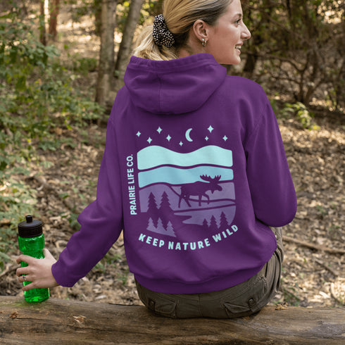Featuring a bold moose silhouette set against a serene forest landscape, this design celebrates adventure, conservation, and life beyond the pavement.