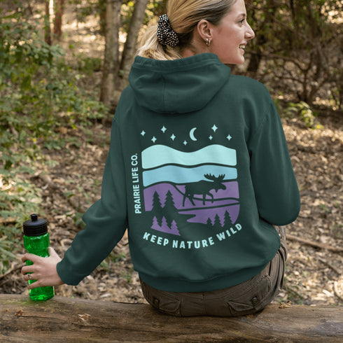 Featuring a bold moose silhouette set against a serene forest landscape, this design celebrates adventure, conservation, and life beyond the pavement.