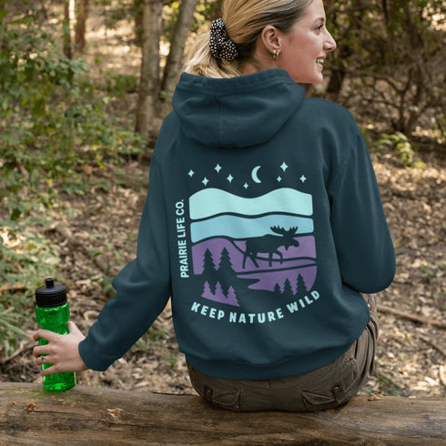 Featuring a bold moose silhouette set against a serene forest landscape, this design celebrates adventure, conservation, and life beyond the pavement.