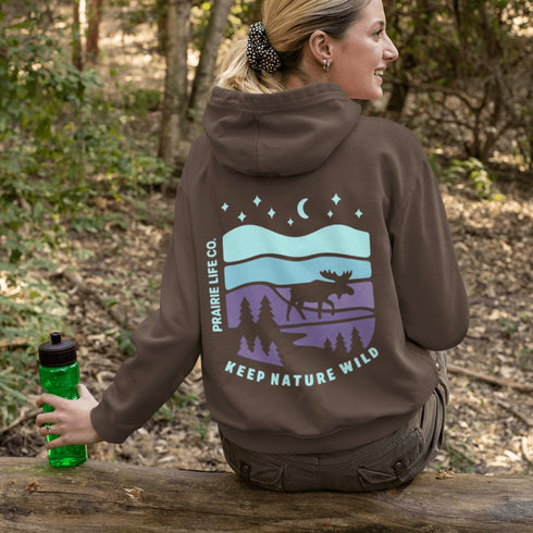 Featuring a bold moose silhouette set against a serene forest landscape, this design celebrates adventure, conservation, and life beyond the pavement.