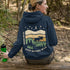 This premium hoodie features a moose silhouette wandering across prairie hills, Pine trees and a clear night sky filled with stars and a crescent moon.