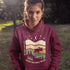 Featuring a bold moose silhouette layered over rolling hills, pine trees, and a starry night sky, this hoodie is a tribute to Canada’s wild landscapes.