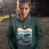 Featuring a moose design paired with a nature-inspired landscape, this hoodie reflects the beauty of Canada’s wild spaces and the importance of protecting them.