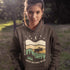 Featuring a bold moose silhouette layered over rolling hills, pine trees, and a starry night sky, this hoodie is a tribute to Canada’s wild landscapes.