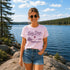 Woman wearing a 'Lake Days' t-shirt by a lake with trees in the background
