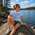 Woman sitting on a rock by a lake wearing a 'Lake Days' t-shirt.