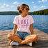 Woman sitting on a dock by a lake wearing a 'Lake Mode' t-shirt.
