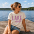 Woman sitting on a dock by a lake wearing a 'Lake Mode' t-shirt.