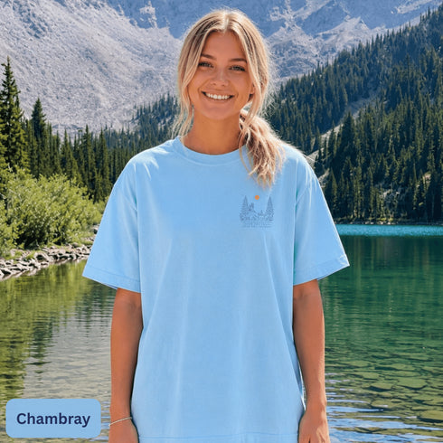 Comfort Colors 1717 unisex t-shirt featuring a coordinating left chest pocket design and large outdoor-inspired back graphic, shown in a lifestyle setting and available in multiple garment-dyed colours.