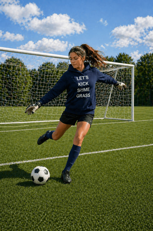 Person kicking a soccer ball on a field with a goalpost in the background