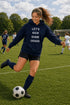 Woman in navy hoodie with 'Let's Kick Some Grass' text on soccer field