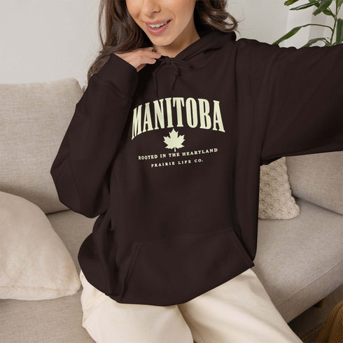 Manitoba Rooted in the Heartland hoodie with maple leaf and vintage collegiate lettering on a unisex Gildan sweatshirt