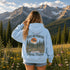 Vintage outdoor hoodie featuring a matching left chest graphic and a large back design inspired by hiking, forests, mountains, and adventure on a premium unisex hoodie displayed in an outdoor lifestyle setting.