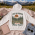 Vintage outdoor hoodie featuring a matching left chest graphic and a large back design inspired by hiking, forests, mountains, and adventure on a premium unisex hoodie displayed in an outdoor lifestyle setting.