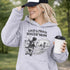 Woman wearing a grey Loud & Proud Soccer Mom hoodie with a vintage soccer scene design, standing on a soccer field with hands in pocket