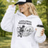 Woman wearing a white Loud & Proud Soccer Mom hoodie with a vintage soccer scene design, standing on a soccer field with hands in pocket
