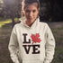 Love Canada hoodie featuring bold black lettering and red Canadian maple leaf graphic on a unisex sweatshirt