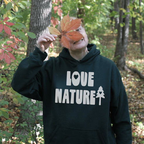 Person wearing a hoodie with 'Love Nature' text in a forest setting