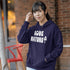 Woman wearing a purple hoodie with 'LOVE NATURE' text, standing outdoors.