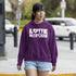 Woman wearing a purple hoodie with 'LOVE NATURE' text on a street.