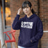 Person wearing a navy hoodie with 'LOVE NATURE' text, standing outdoors against a brick wall.