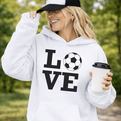 Hoodie with bold LOVE design featuring a soccer ball replacing the O, worn by woman holding coffee cup outdoors